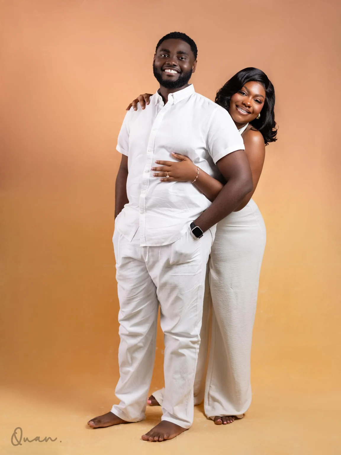 Tess embracing Kwaku from behind, both in white